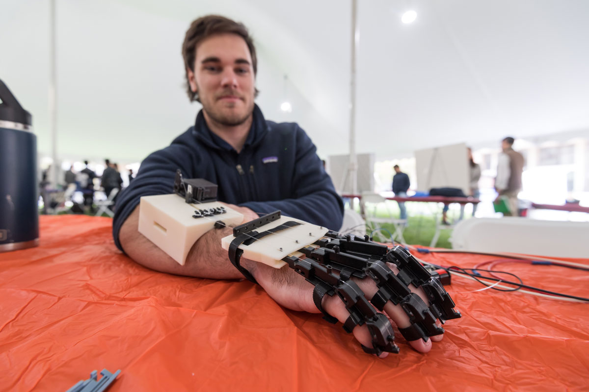 A man with a robotic hand rests it on a table, showcasing innovative research from the University of Rochester.