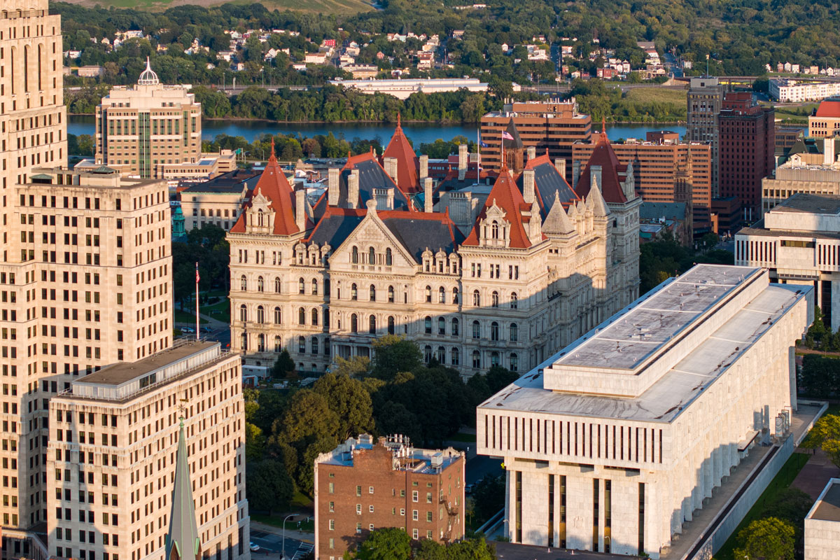 A bustling cityscape featuring numerous buildings and a prominent clock tower, representing New York state government.