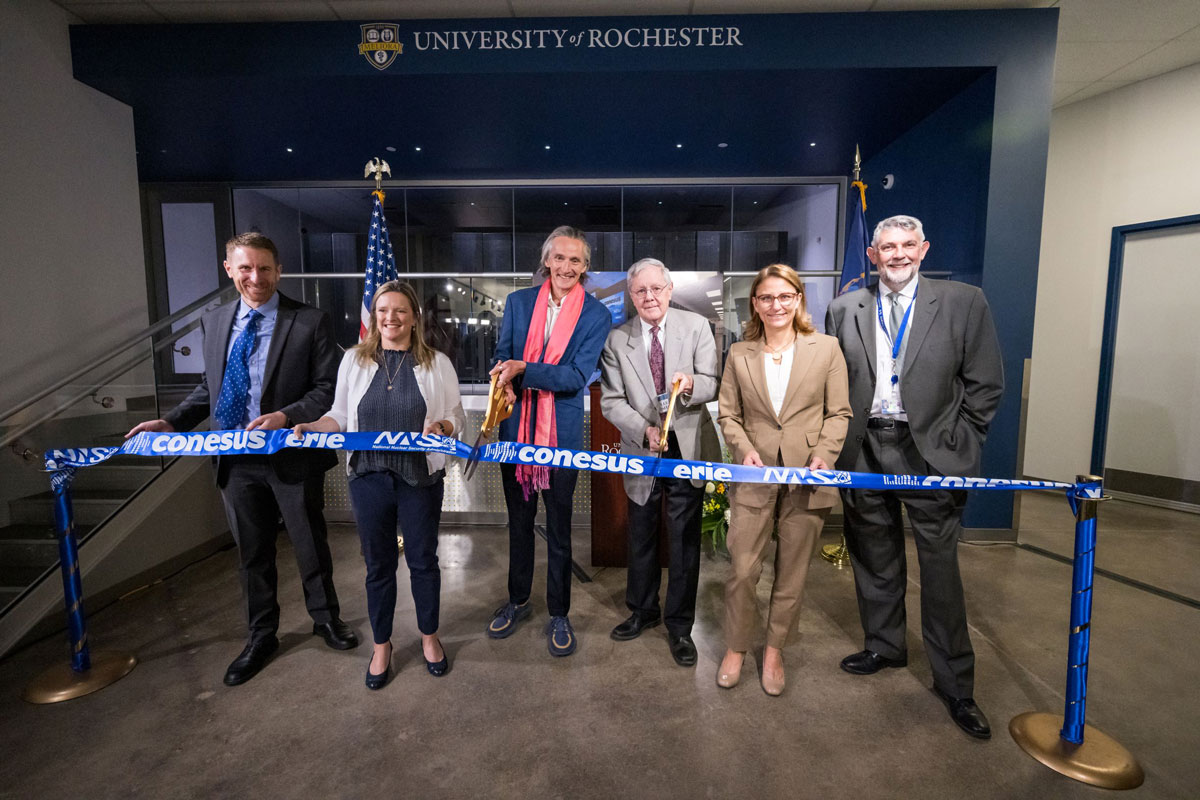 A diverse group of individuals stands proudly in front of a large ribbon, ready to celebrate a significant opening event.