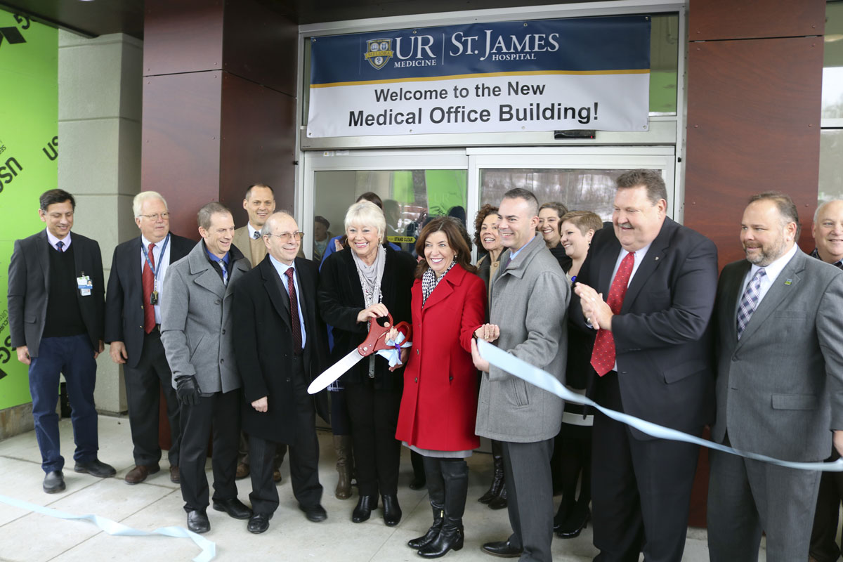 A diverse group of individuals gathered for a ribbon-cutting ceremony, celebrating a new beginning with smiles and anticipation.